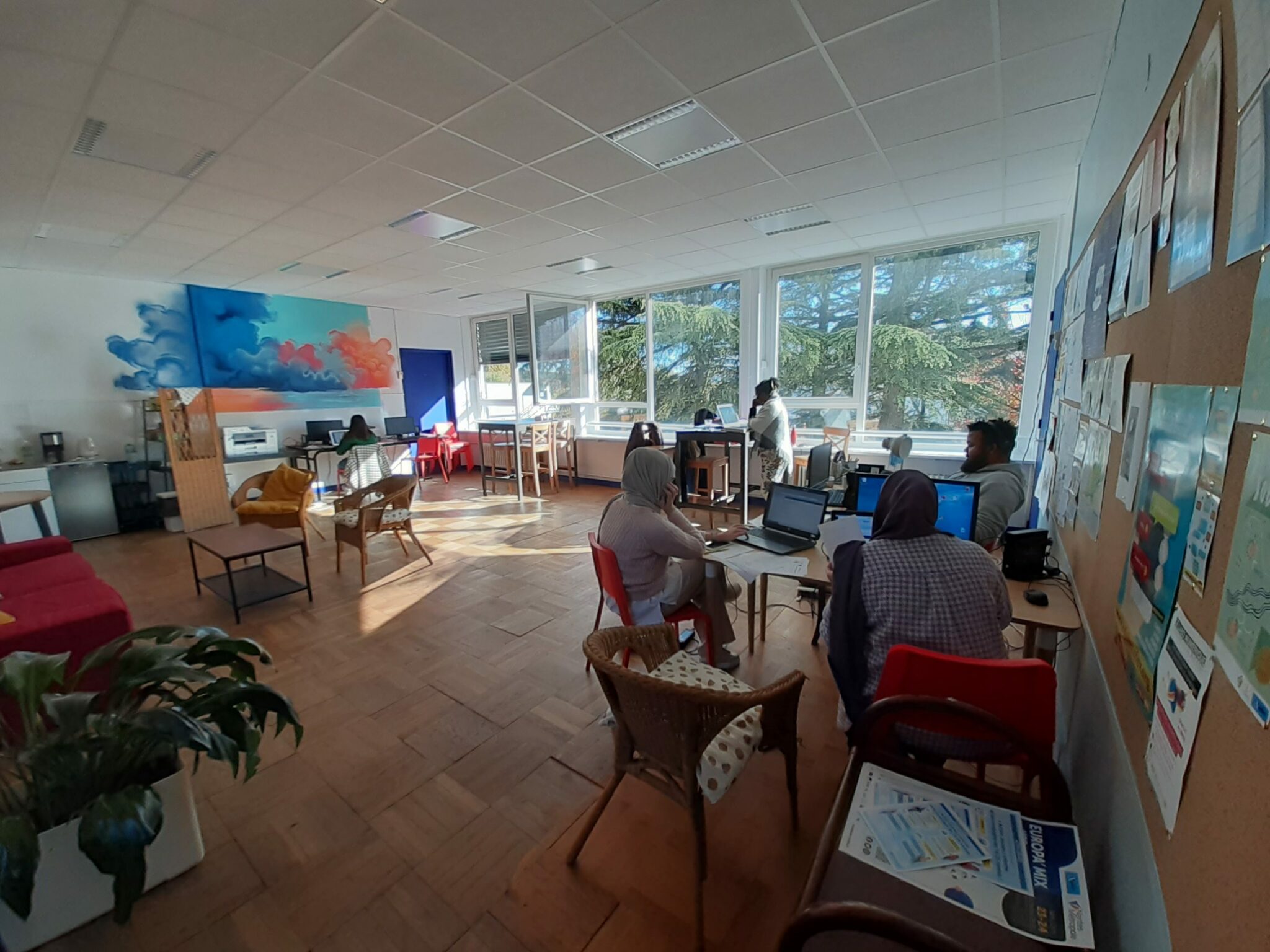 Photo de la salle principale de la pépinière. Au premier plan on voit des jeunes installés à un ilôt avec des ordinateurs portables
